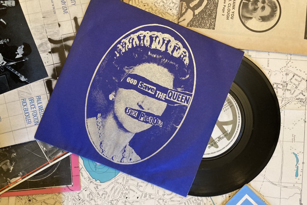 Picture sleeve cover of Sex Pistols "God Save the Queen" with vinyl 7" record of Hudson Ford "Floating in the Wind"
